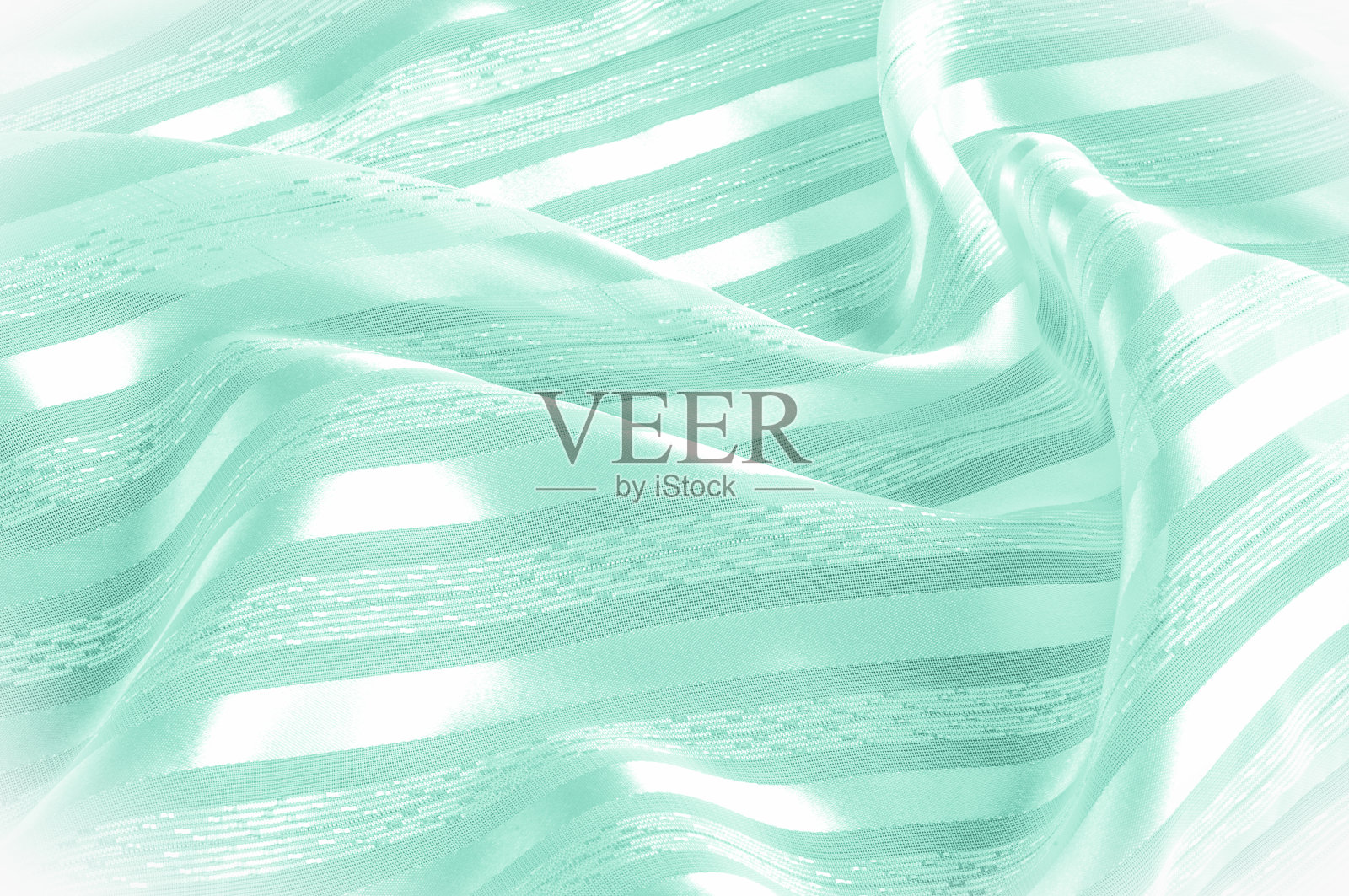 背景纹理、图案。绿色丝织物，带浅条纹。绿色的布。光滑优雅的绿色缎子背景。照片摄影图片