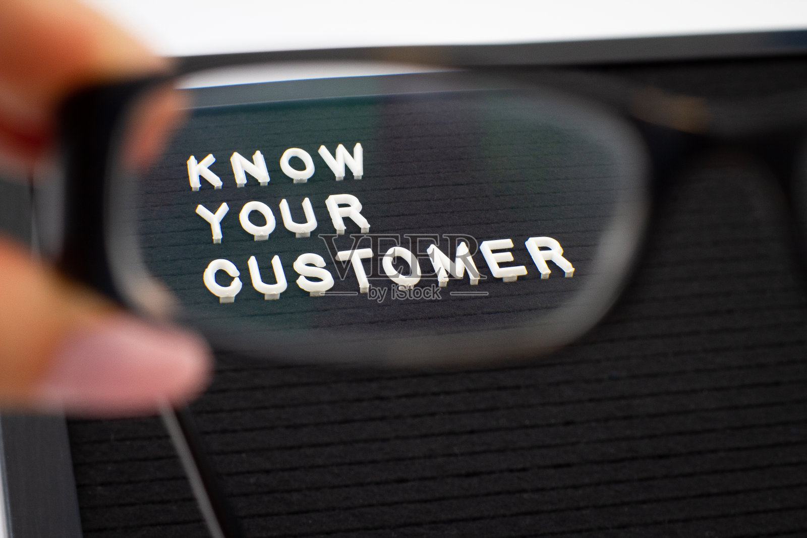 了解你的客户-经营理念，通过镜片增强眼镜，这是由女性的手，白色的文字信息在黑板上照片摄影图片