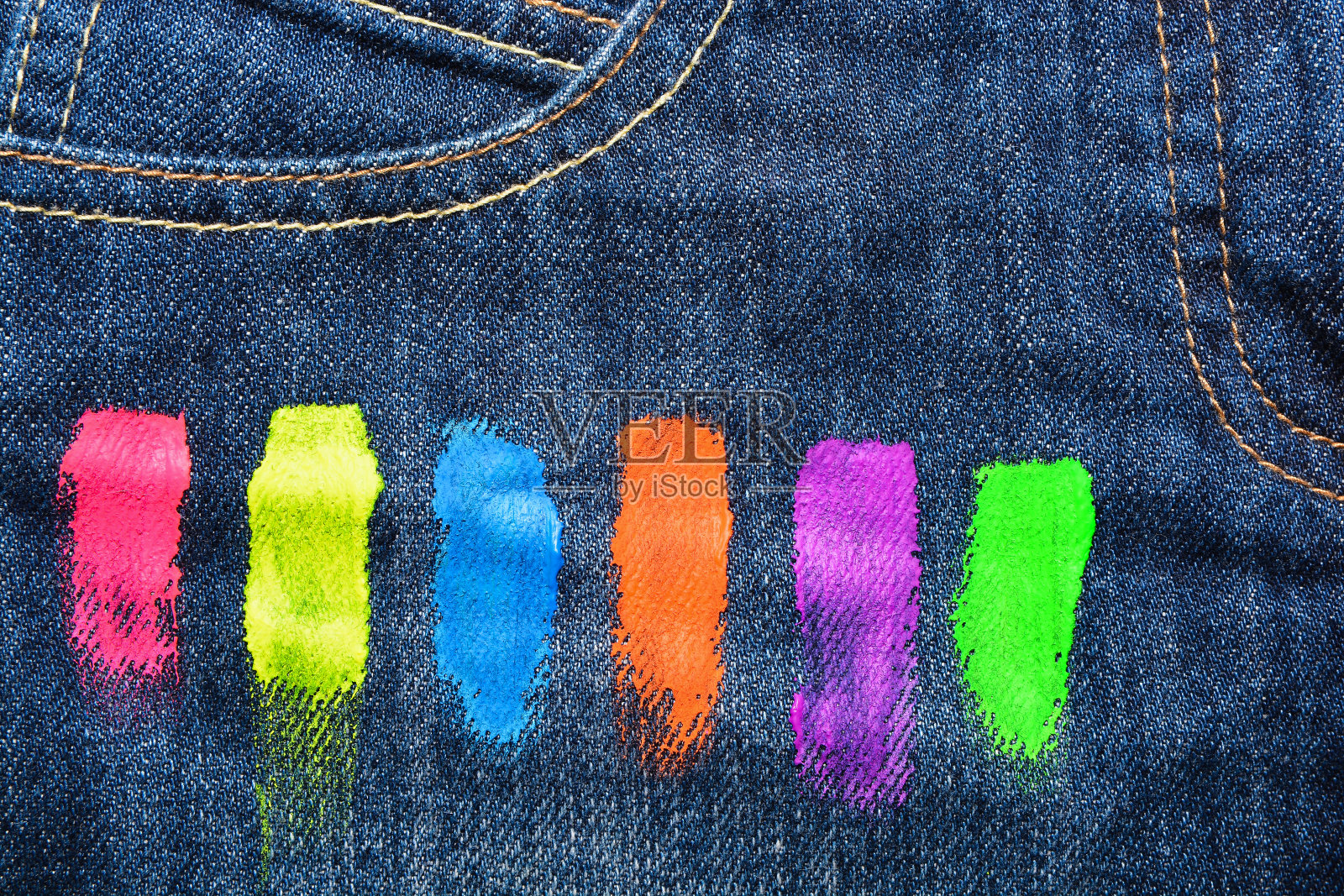 用荧光水粉颜料涂抹牛仔布的纹理。抽象的背景照片摄影图片