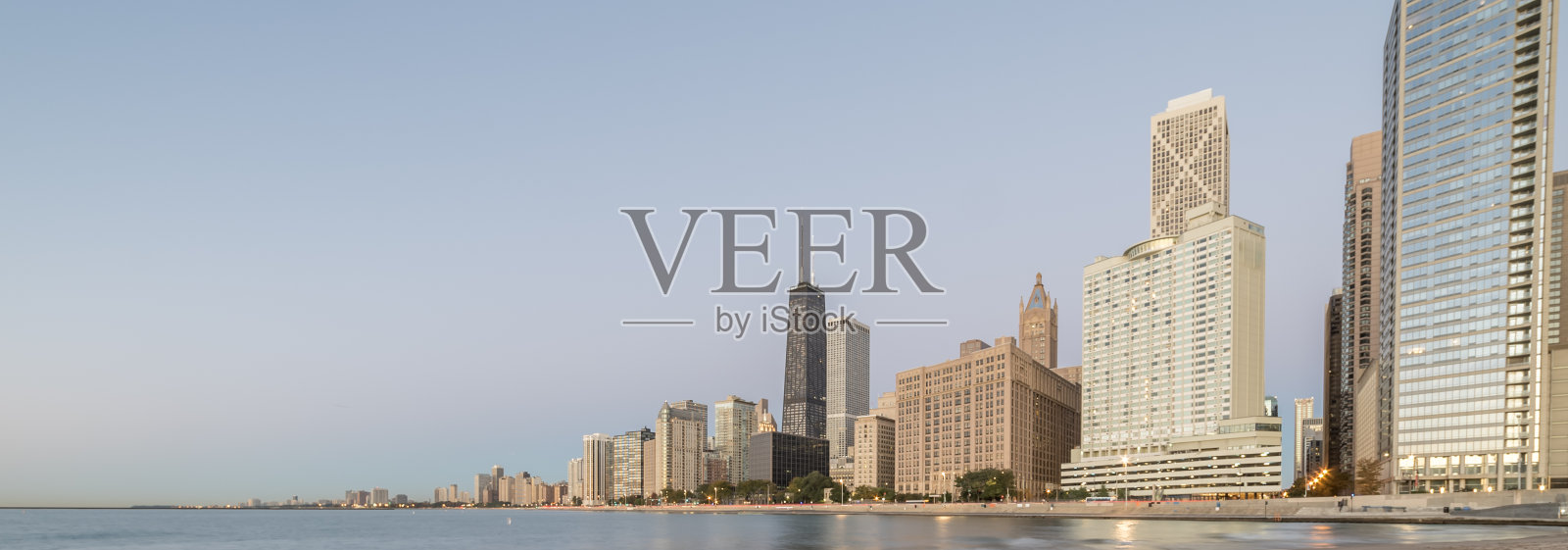 日出时芝加哥摩天大楼在密歇根湖上的全景反射照片摄影图片