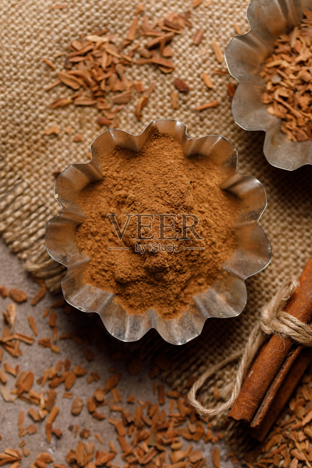 肉桂在烘烤罐和肉桂棒上的散射与织物下的粗麻布纹理背景。照片摄影图片