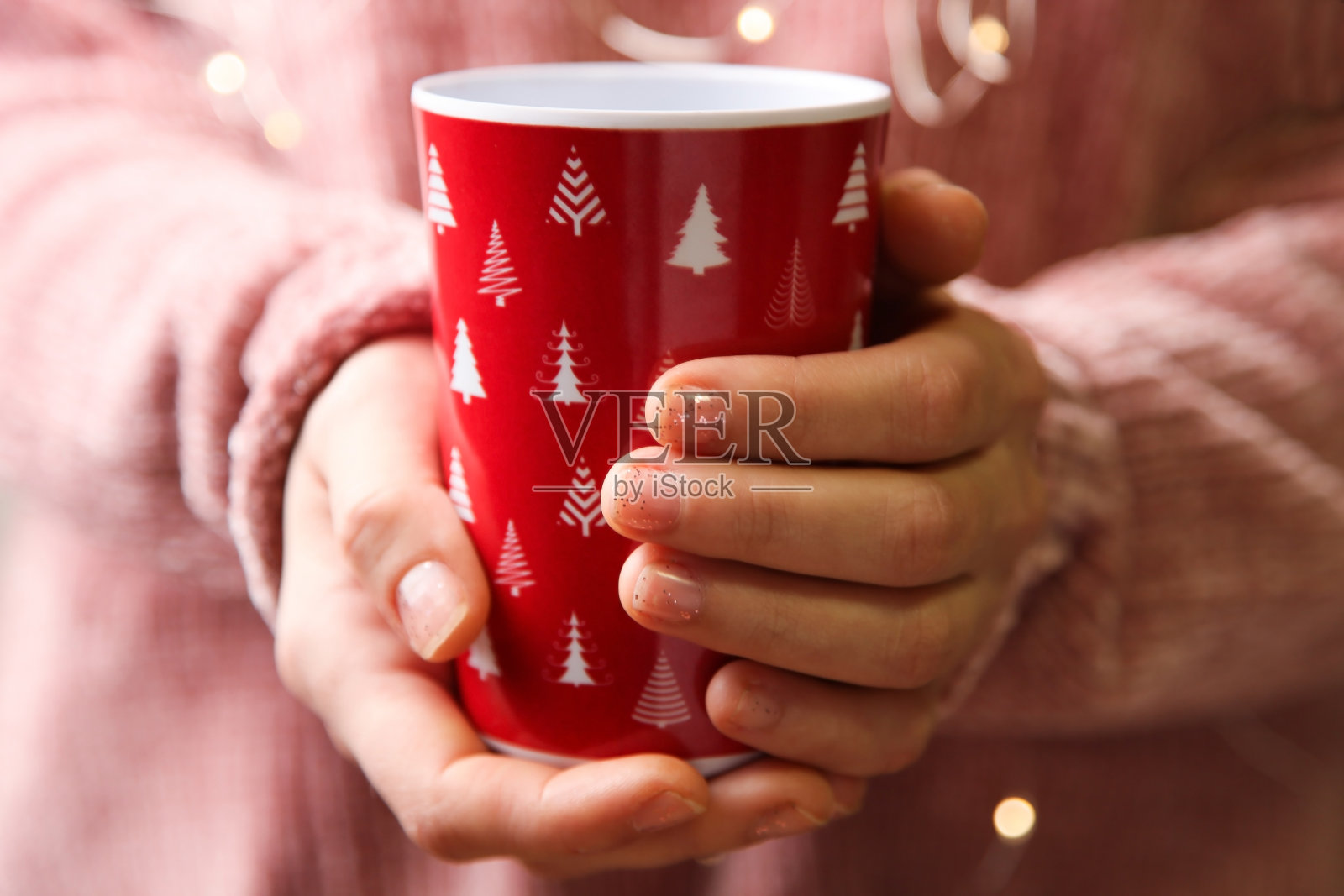 手里拿着红色的圣诞杯。照片摄影图片