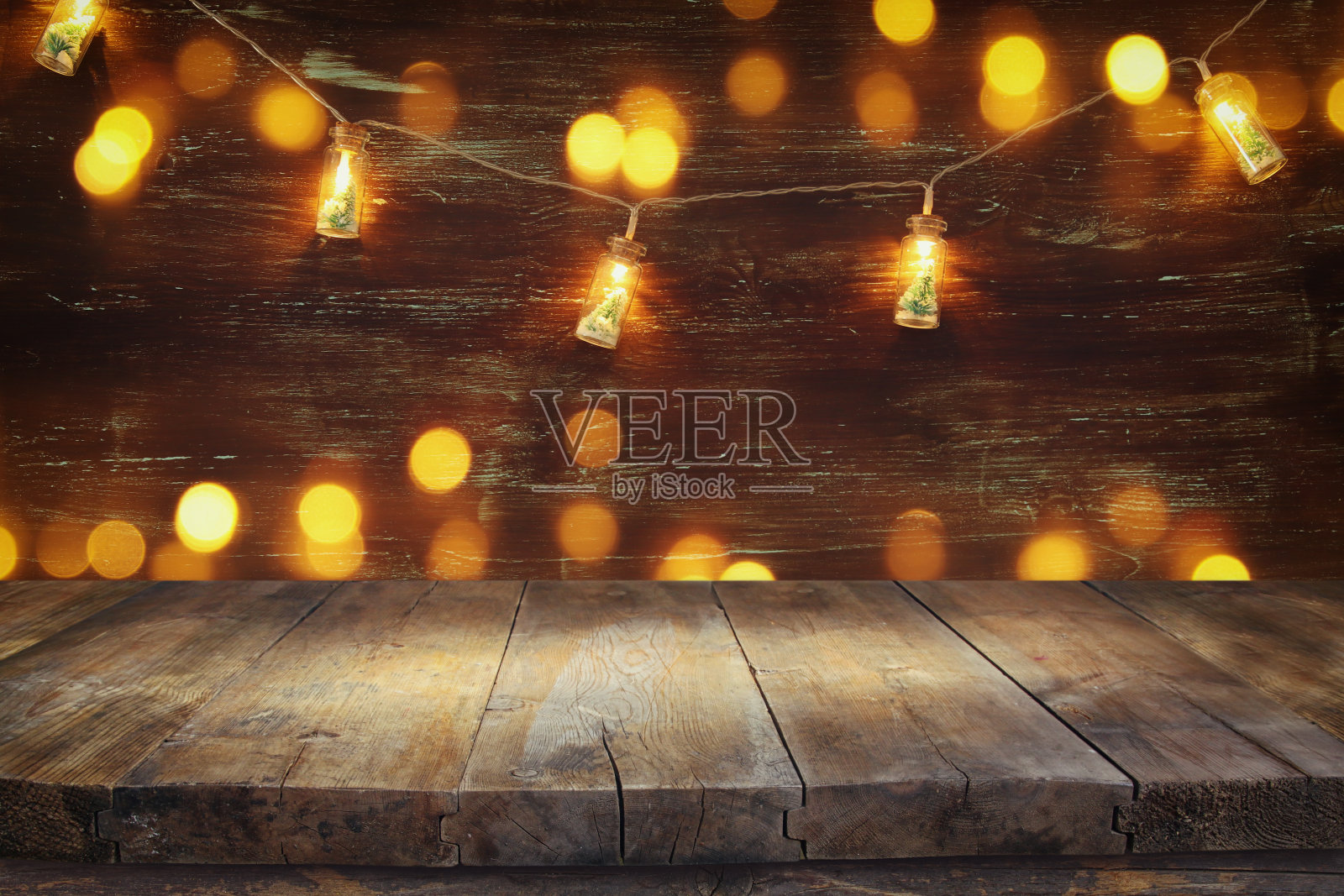 空桌子前的圣诞树在马森瓶花环灯木制背景。照片摄影图片