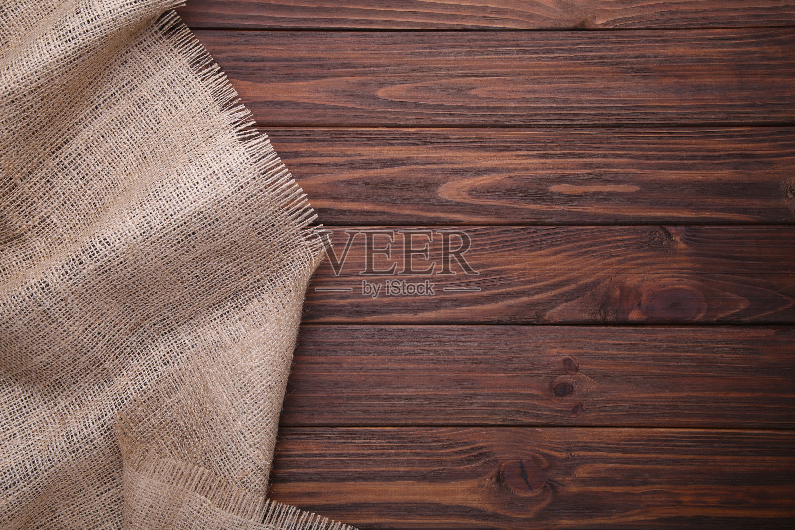 天然麻袋布上的棕色木制背景。棕色木桌上的帆布照片摄影图片