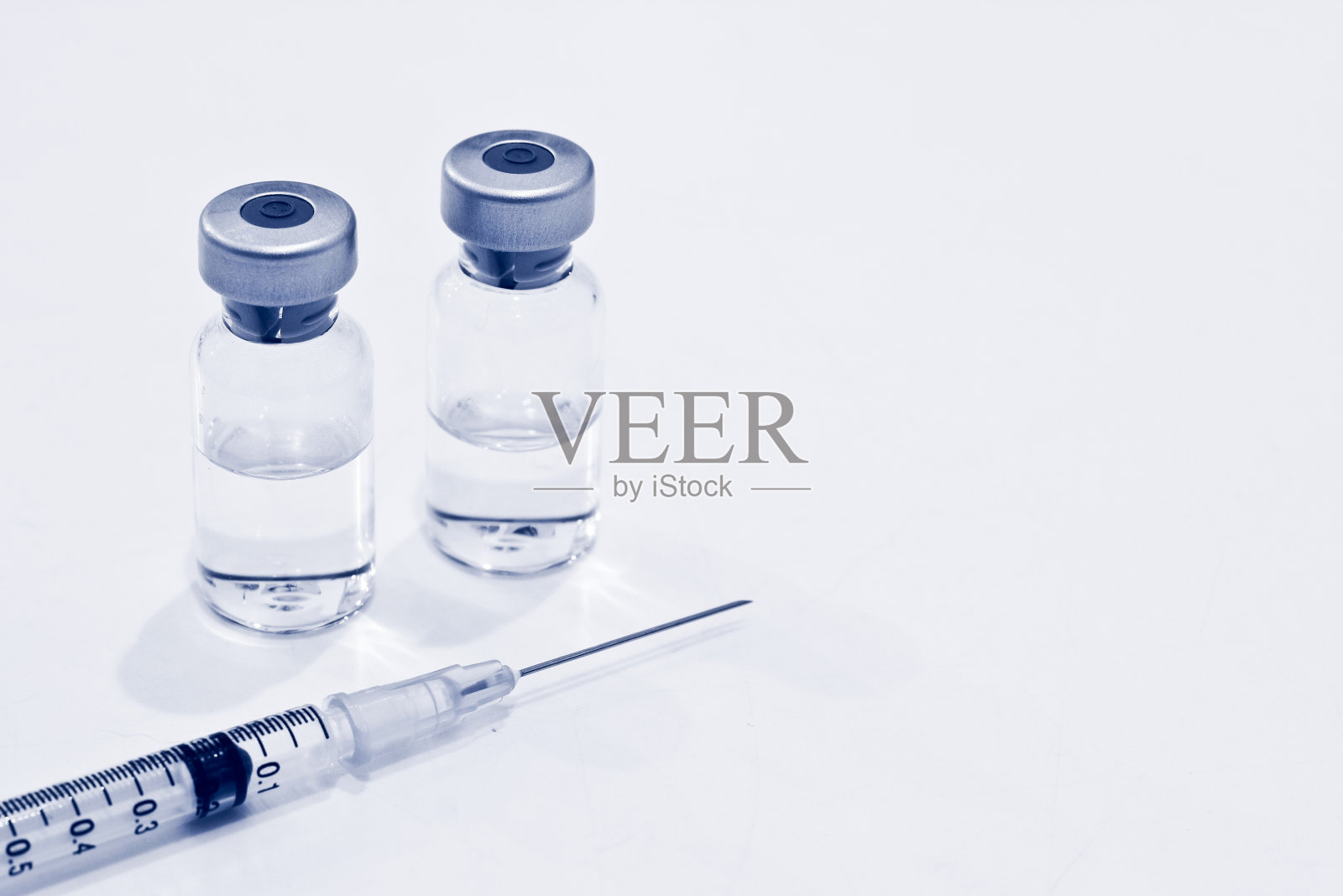 小瓶药物或疫苗和1ml塑料注射器与针隔离在白色背景，蓝色调照片摄影图片