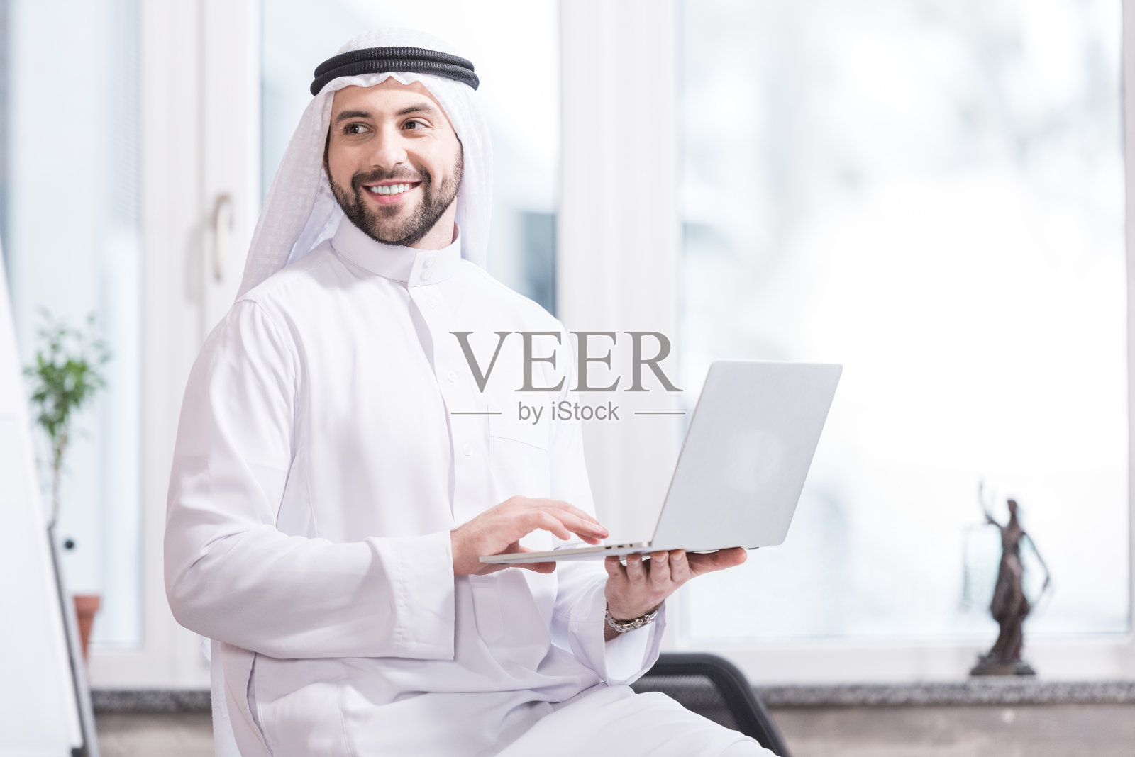 阿拉伯商人在现代办公室里拿着笔记本电脑照片摄影图片