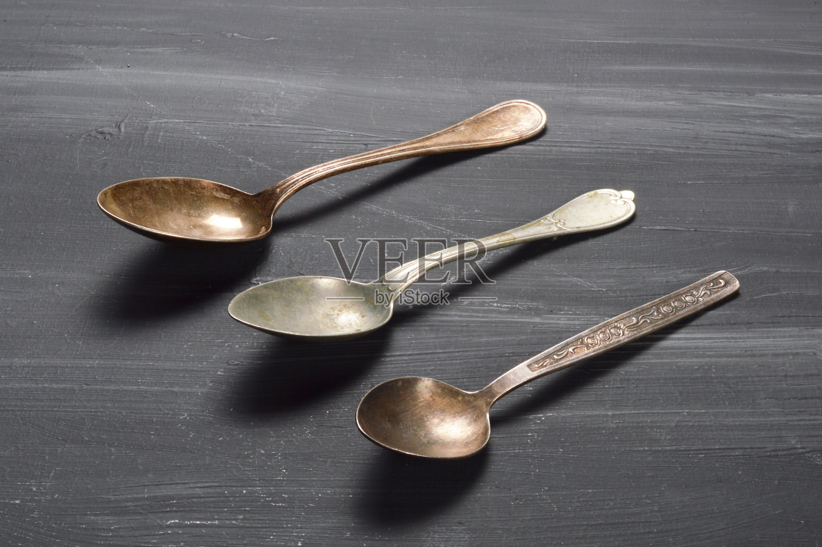 黑色木头桌子上的旧汤匙照片摄影图片