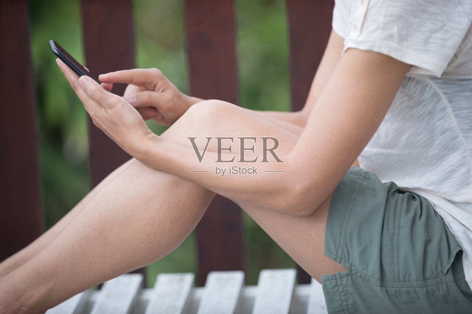 女人用手机坐在日光浴床上照片摄影图片