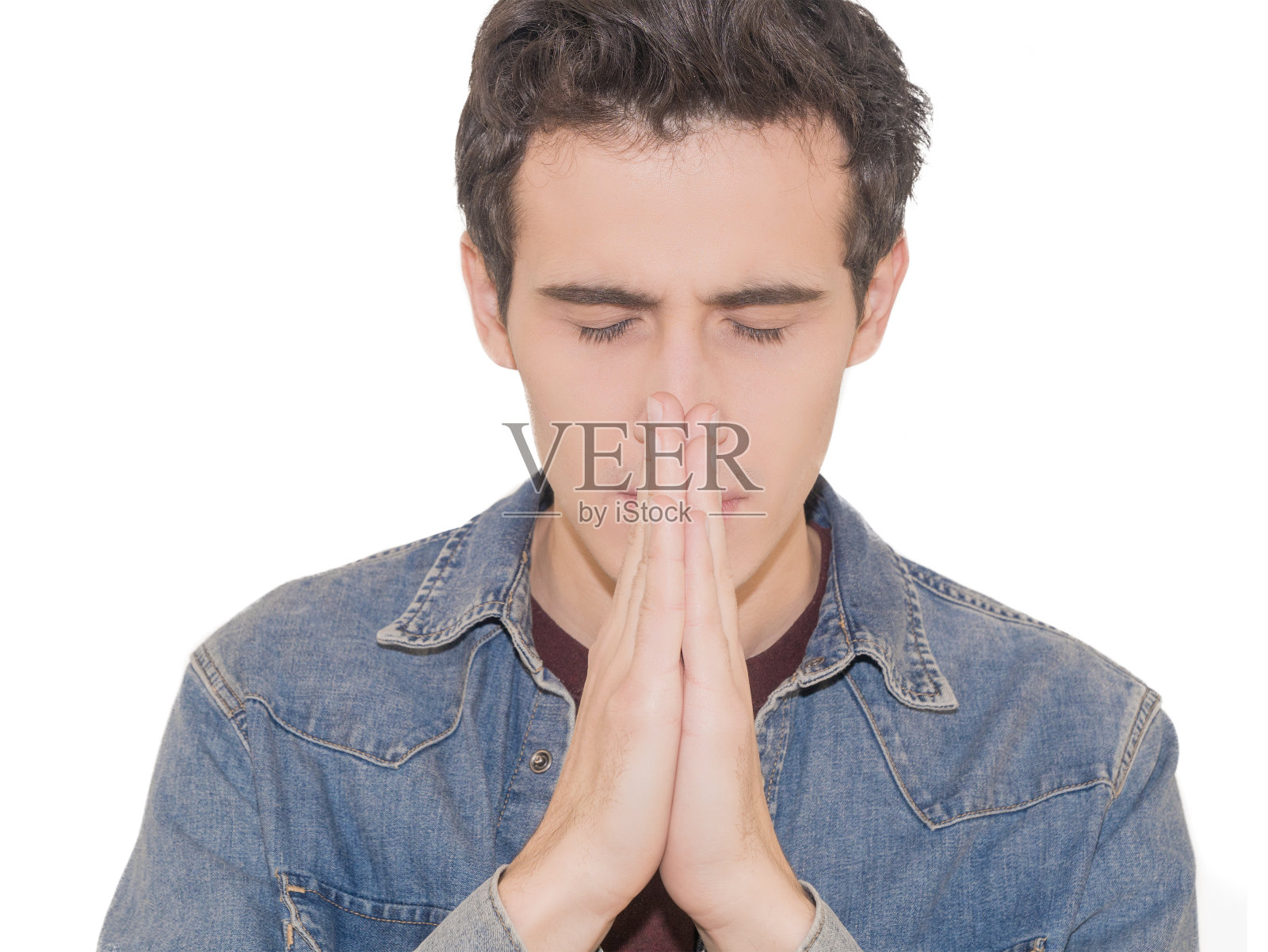 年轻人穿着随意，孤立在白色背景下，双手合十祈祷或冥想，看起来很放松和平静照片摄影图片