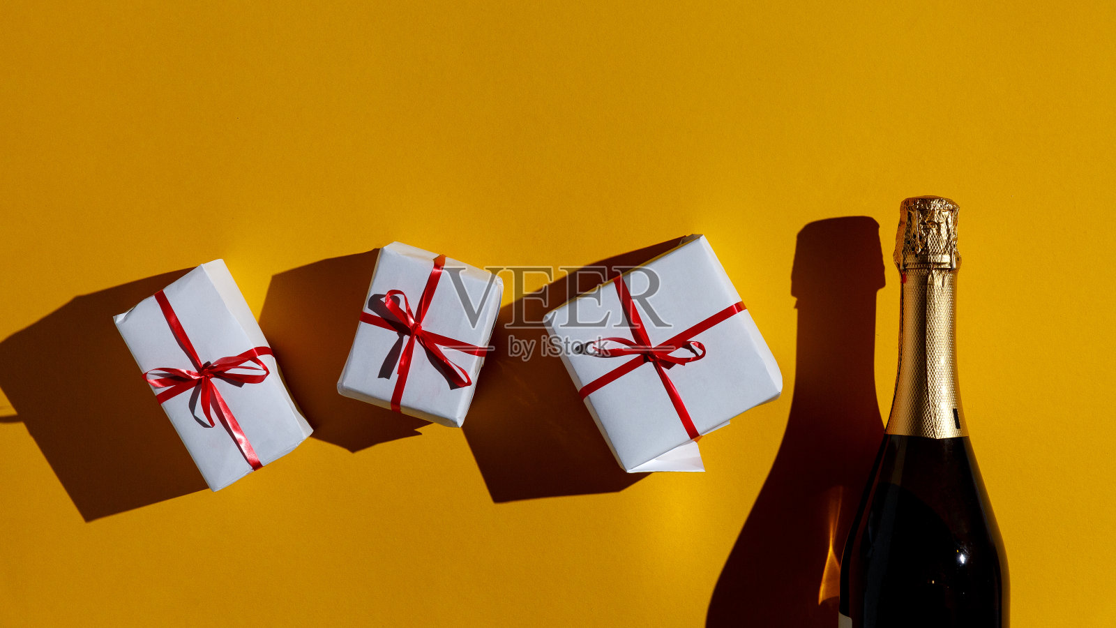 圣诞快乐，新年快乐2019概念。黄色背景上的香槟酒和礼品盒，俯视图与复制空间照片摄影图片