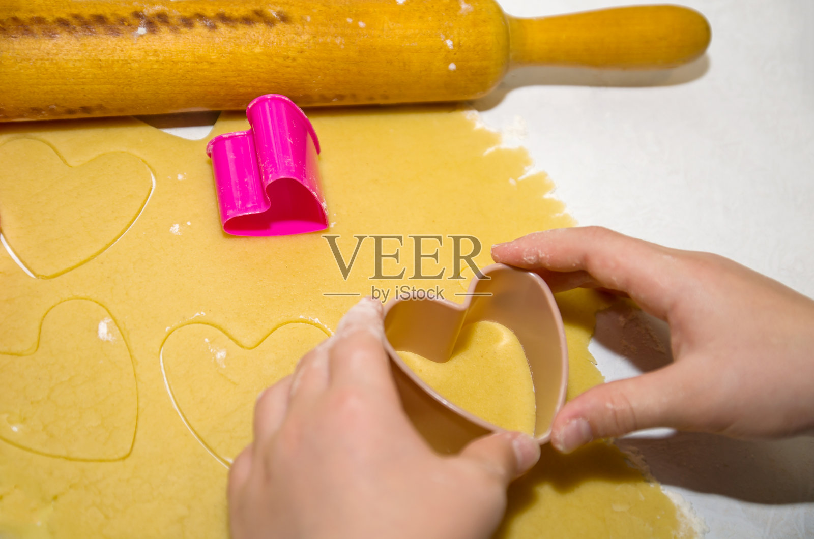 两只手用饼干切刀做成心形的面团照片摄影图片