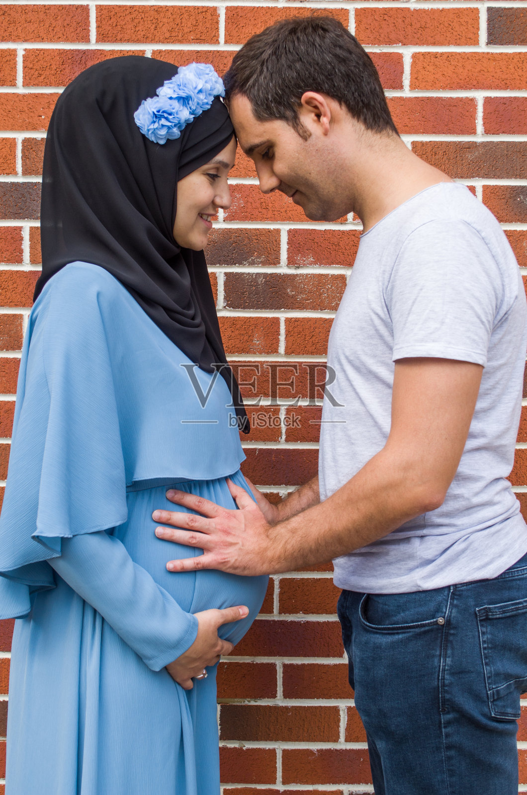 年轻男人触摸他怀孕妻子的肚子照片摄影图片