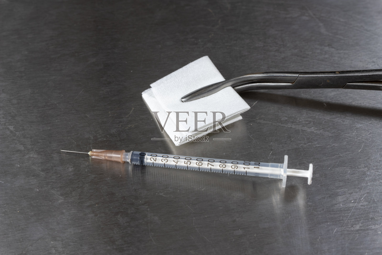 消毒棉签，钳子和医用注射器放在医院的桌子上。医生办公室里的配件。光背景。消毒棉签，钳子和医用注射器放在医院的桌子上。医生办公室里的配件。光背景。照片摄影图片