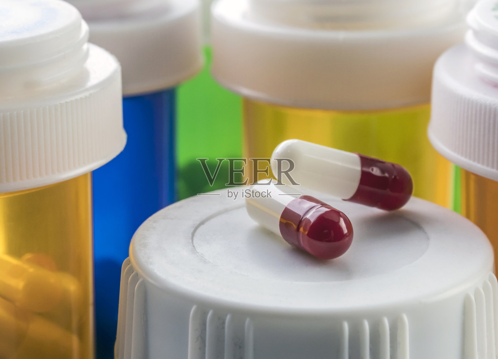 两粒红白相间的胶囊上有一瓶药，概念形象照片摄影图片