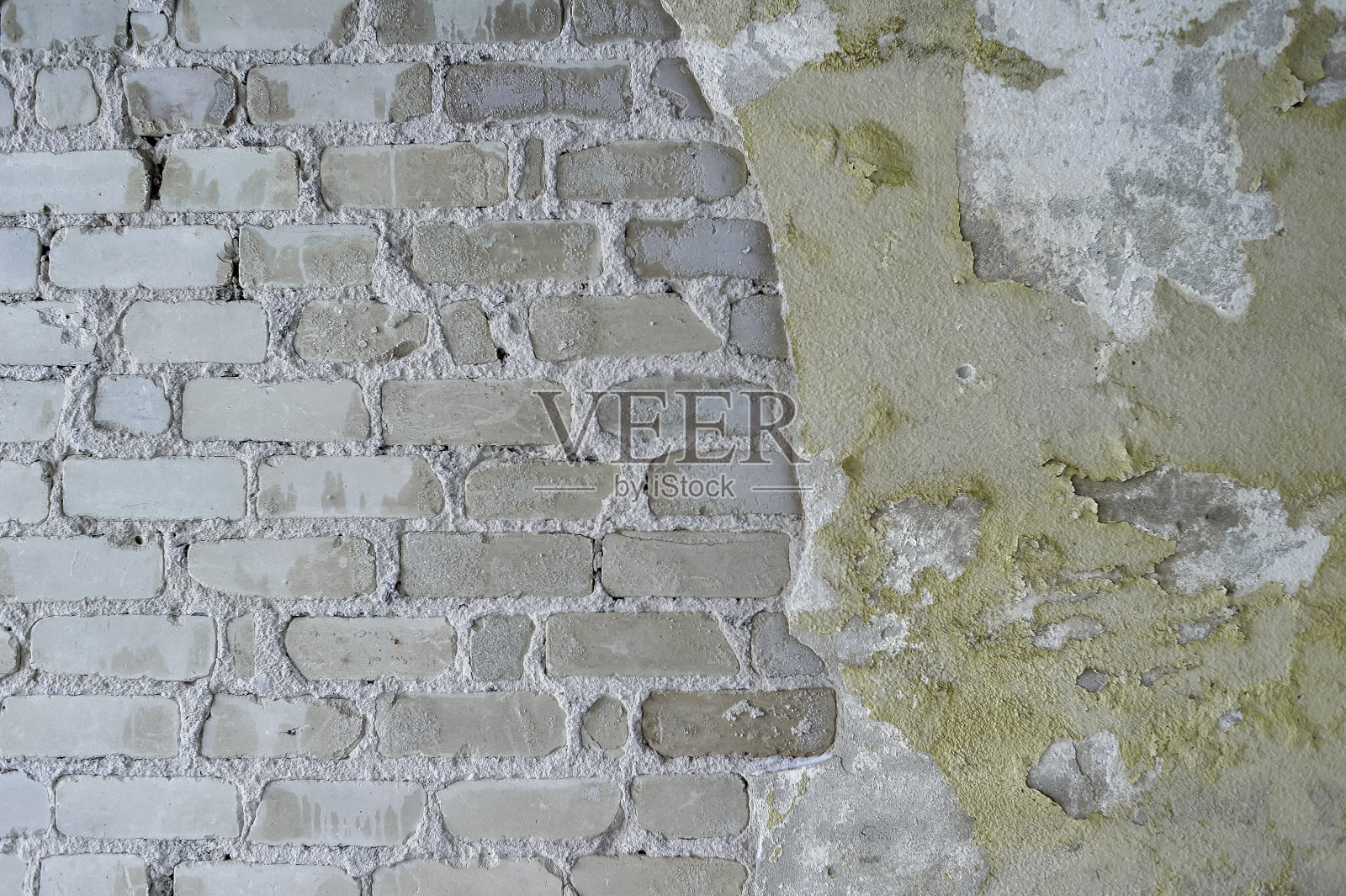 灰色的砖墙上有明显的灰泥残余，部分覆盖着剥落的旧油漆。背景照片摄影图片