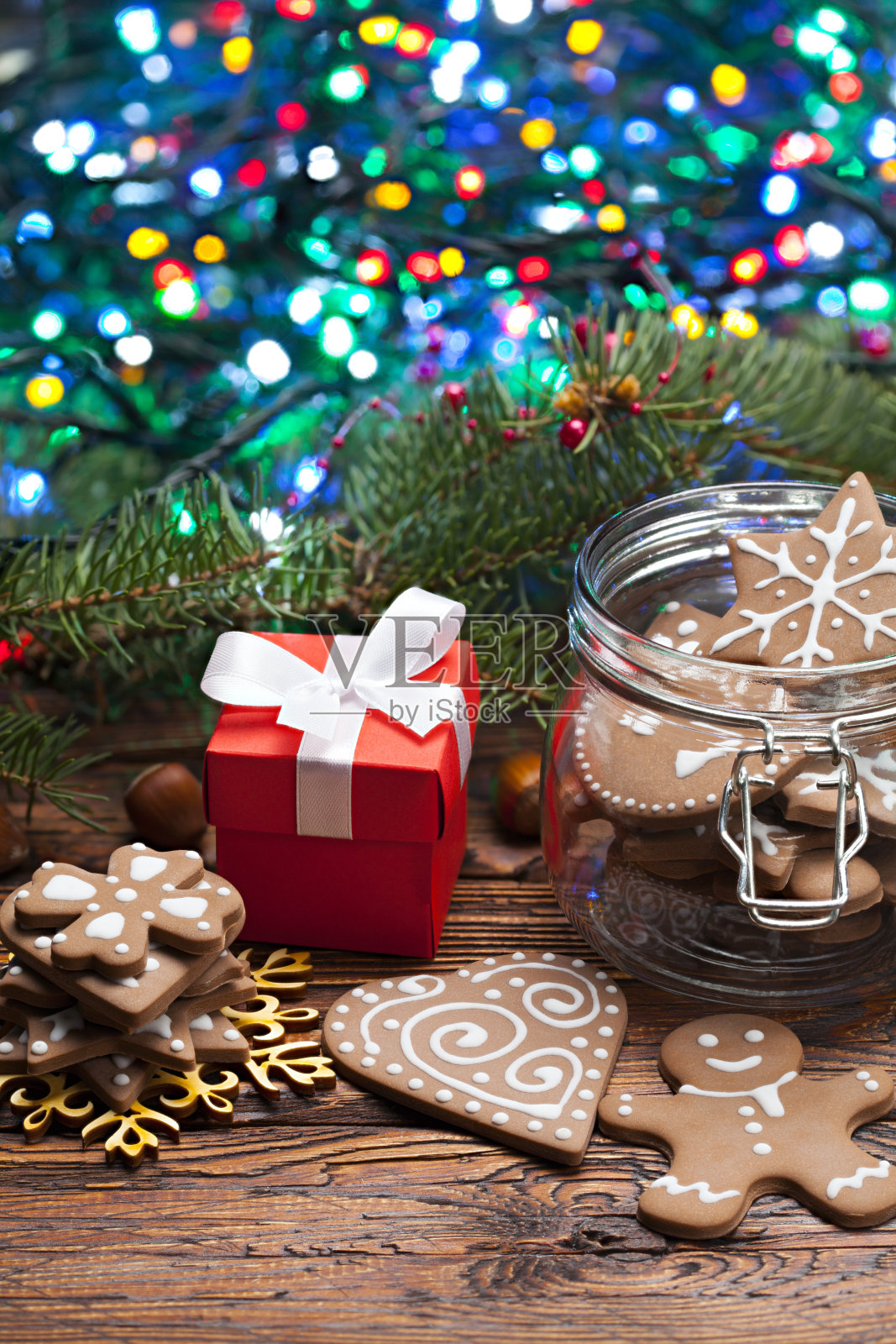 装饰的姜饼圣诞饼干，礼品盒和云杉树枝与许多彩灯木制桌子照片摄影图片