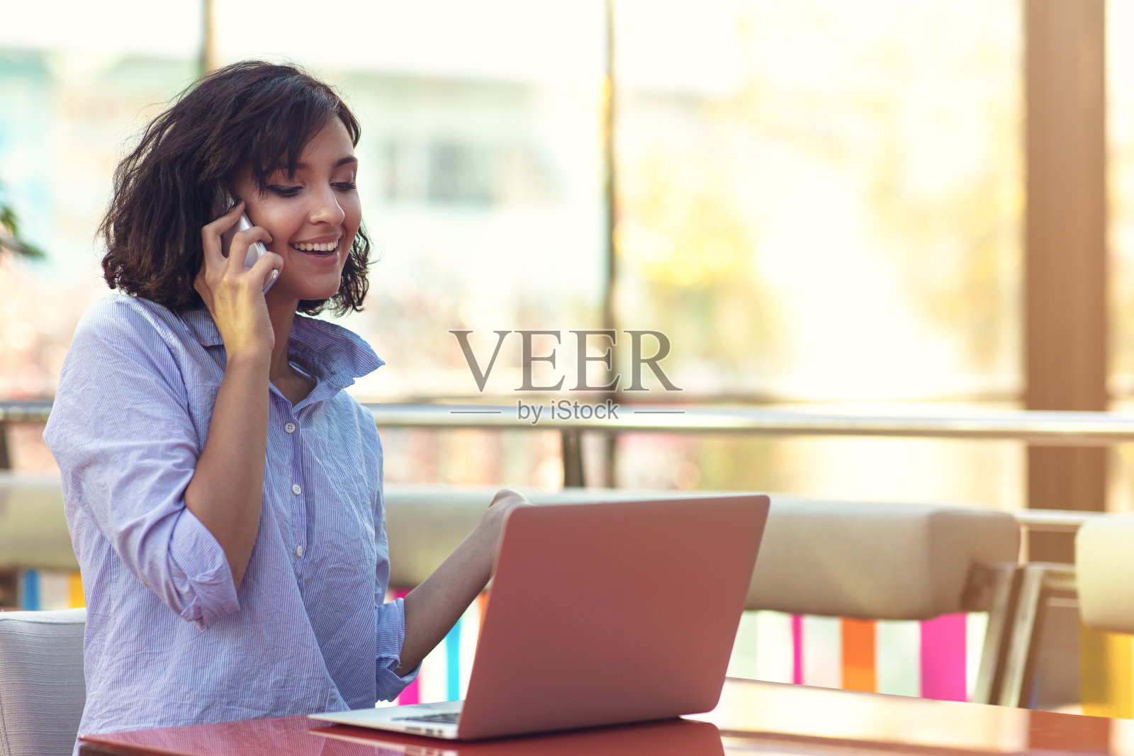 肖像欢快的年轻女士坐在咖啡馆与手机照片摄影图片