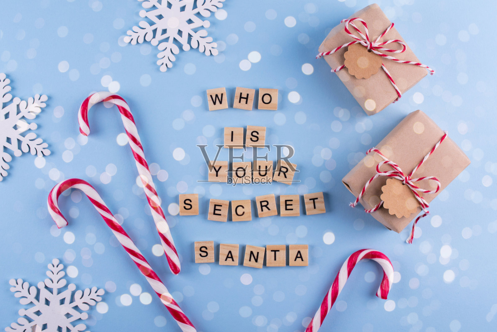 秘密圣诞游戏。包装的礼盒与注意事项，糖果手杖在蓝色柔和背景俯视图copyspace。谁是你的神秘圣诞老人照片摄影图片