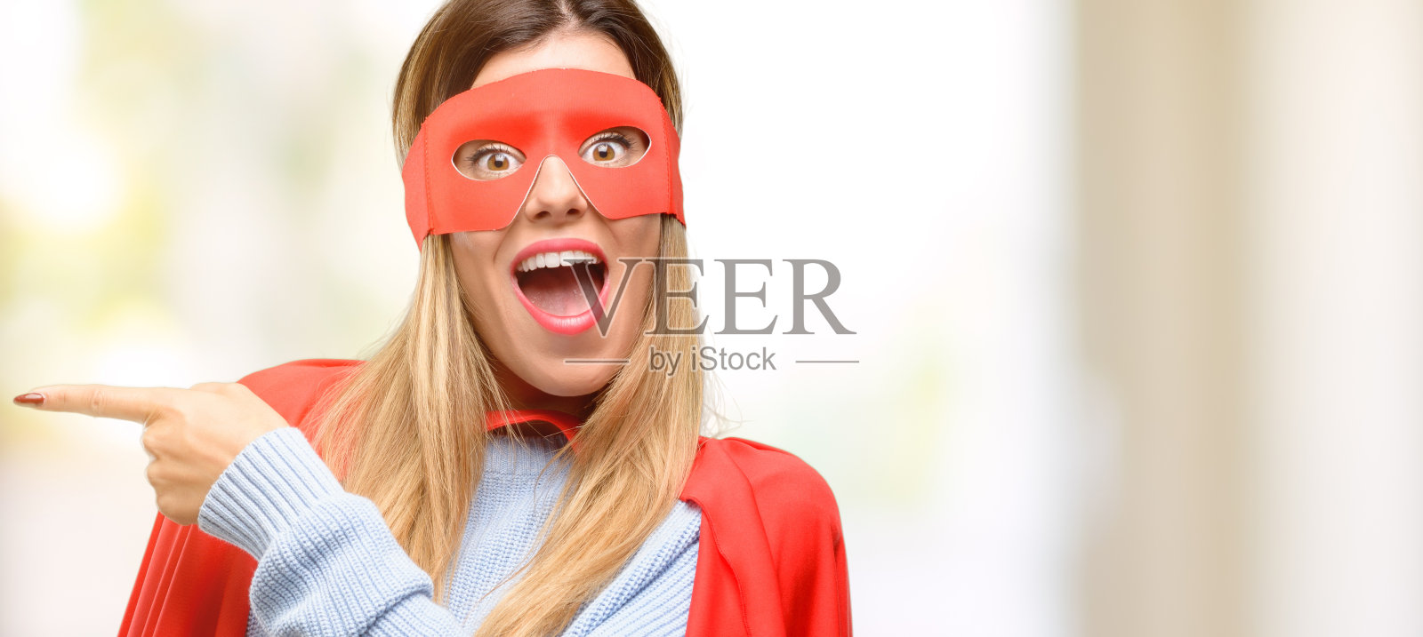 年轻的女超人用手指向一边照片摄影图片