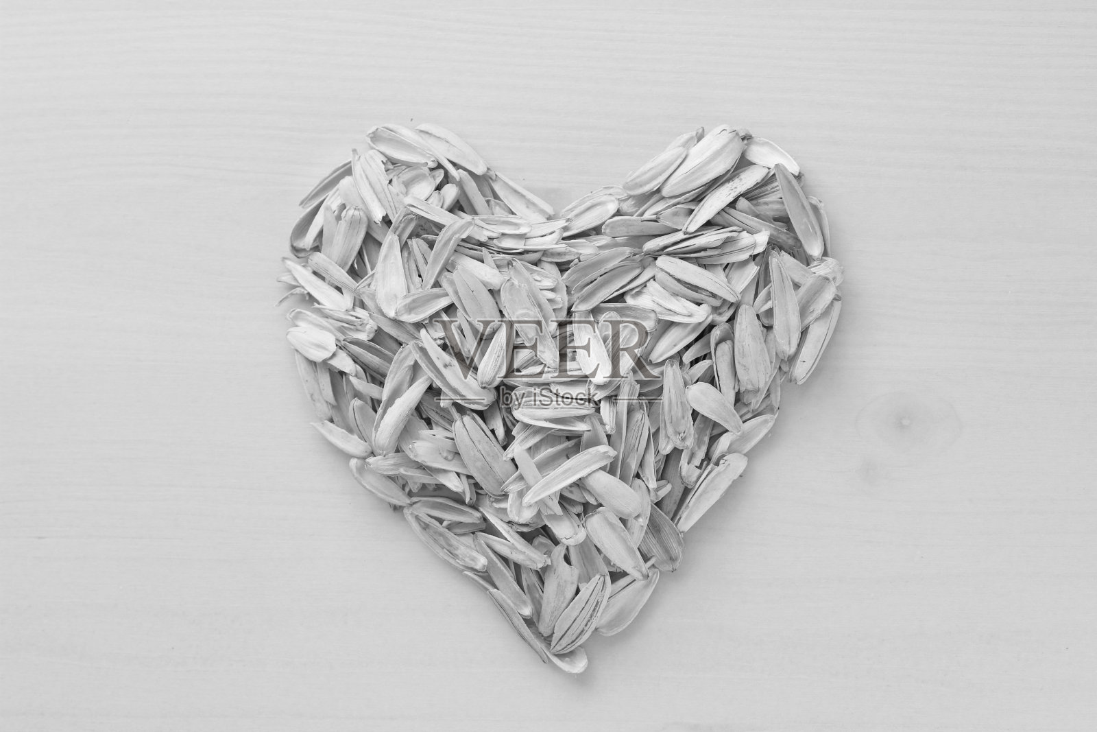 用很多葵花籽做成的心。白色背景上的种子废料堆。白色的葵花籽。有创造力,封面,不寻常的。垃圾,垃圾照片摄影图片