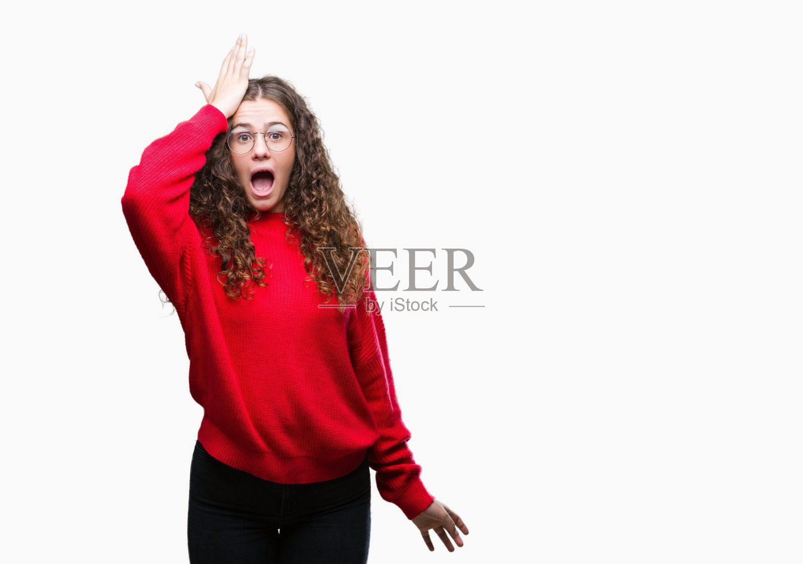 美丽的黑发卷曲的小女孩戴着眼镜和冬天的毛衣越过孤立的背景惊讶与手头上的错误，记得错误。忘记，糟糕的记忆概念。照片摄影图片