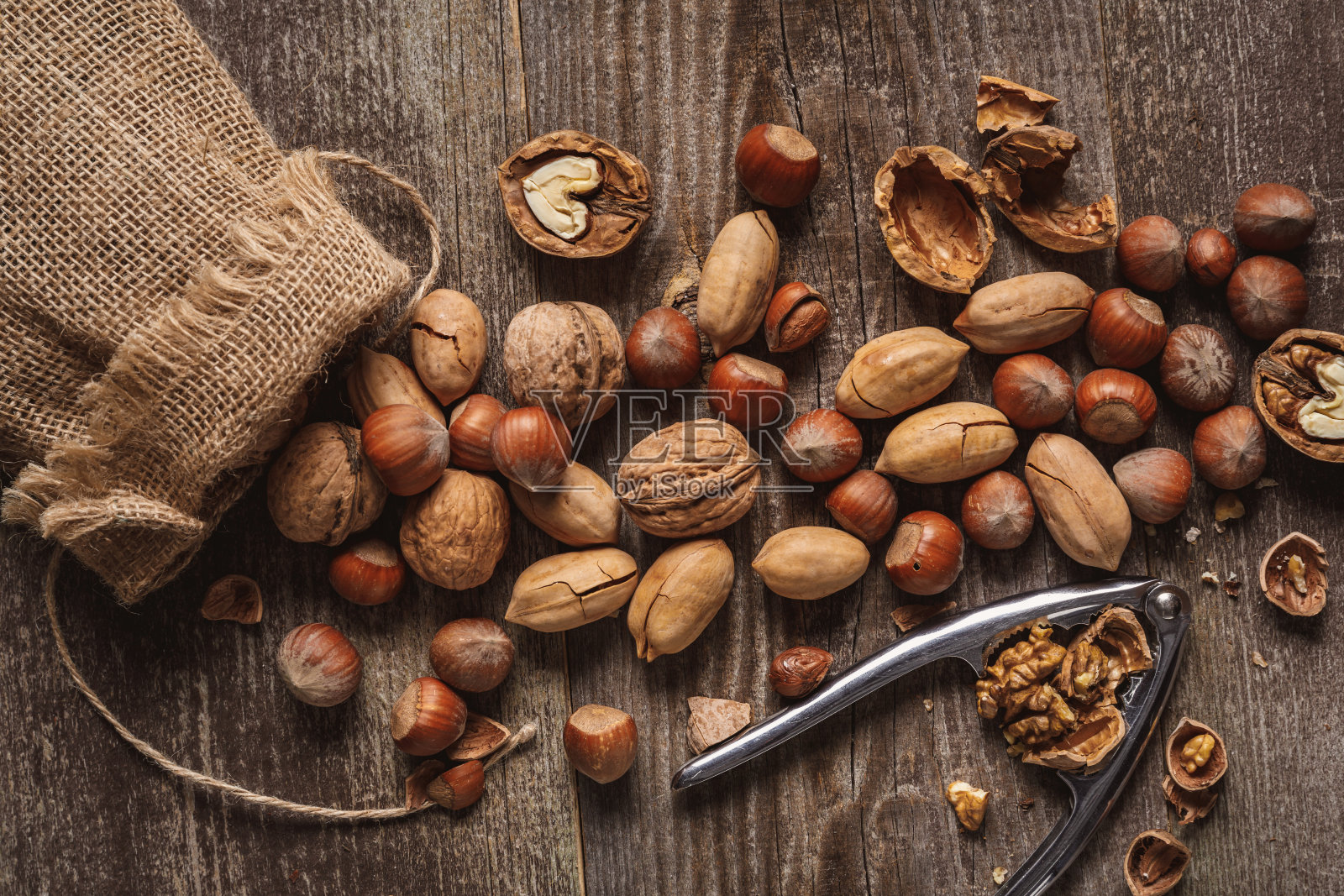木桌面上平铺着坚果、胡桃夹子和麻袋照片摄影图片