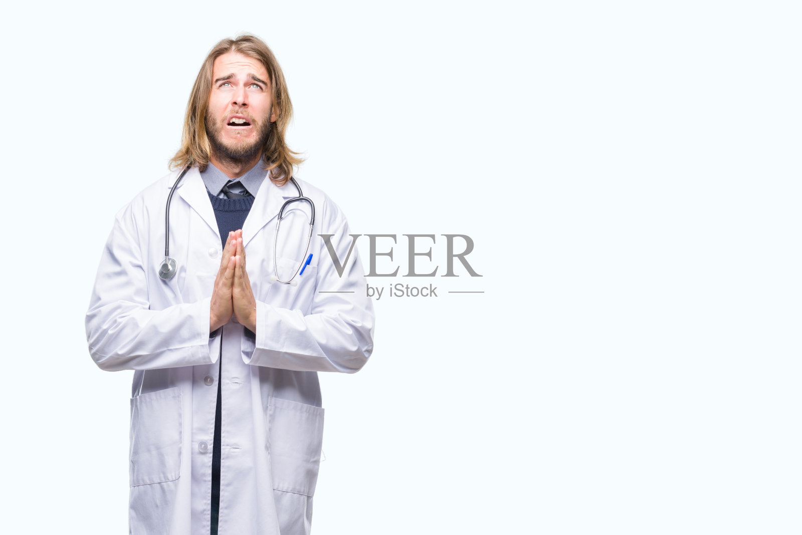 年轻英俊的长头发的医生男人孤立的背景乞求和祈祷与希望的表情在脸上非常情绪化和担心。请求宽恕。宗教的概念。照片摄影图片