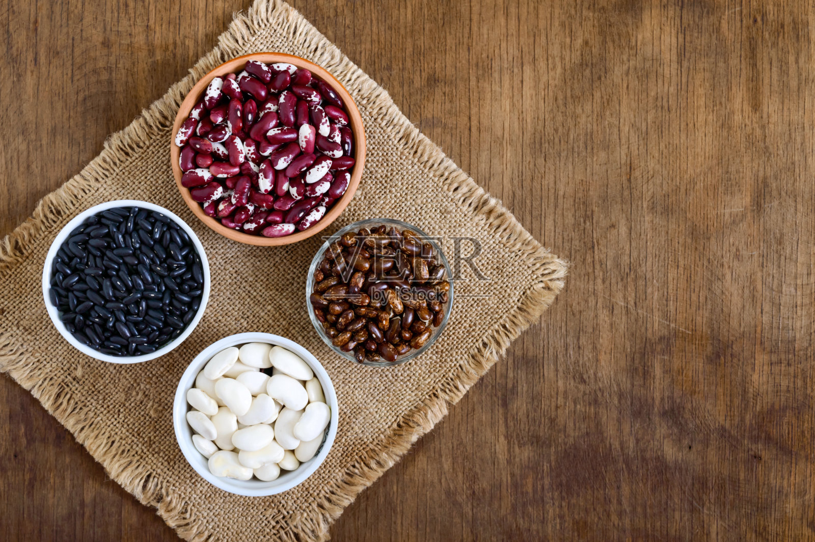 木桌上的碗里各色各样的生豆子。健康食品、节食、营养理念。豆类-纯素蛋白质来源。照片摄影图片