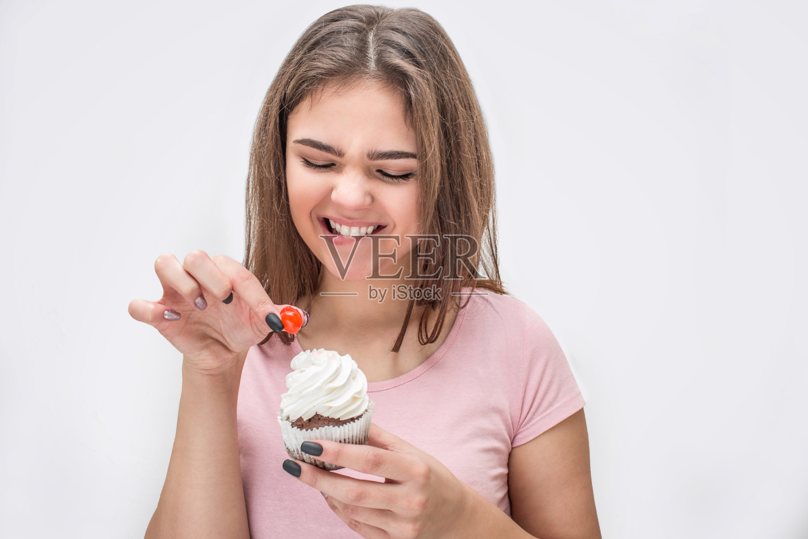 快乐的少妇捧着小红甜甜上面的蛋糕。她的微笑。孤立在白色背景上。照片摄影图片