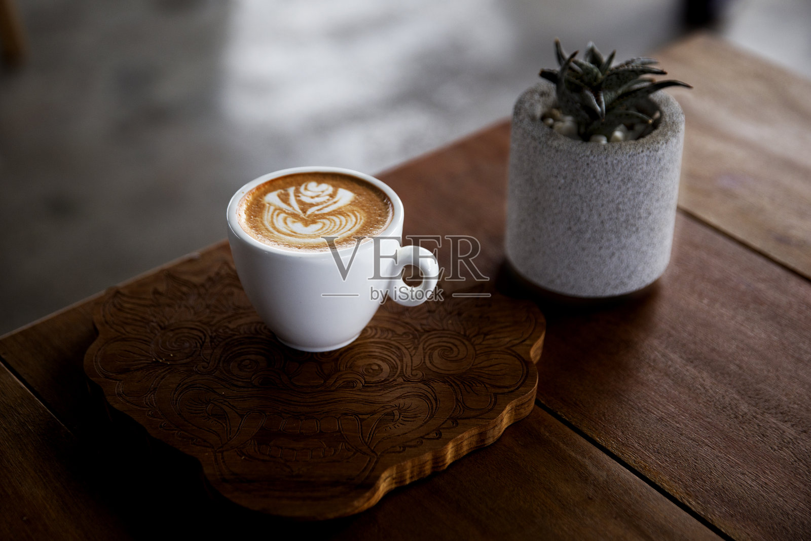 一杯卡布奇诺与仙人掌在灰色壶木背景。照片摄影图片