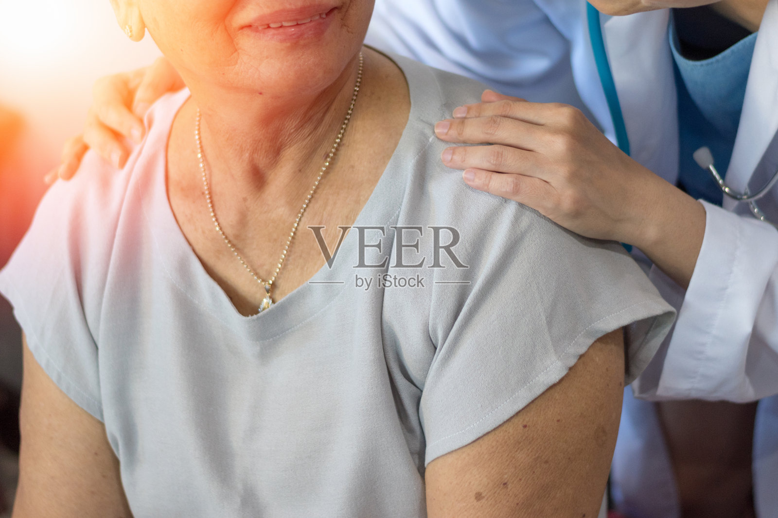 在养老院，老年女性与年轻的护工手牵手。老年医生或老年医学概念。医生在医院检查时，医生开心的把手放在老人老人的身上安慰老人照片摄影图片