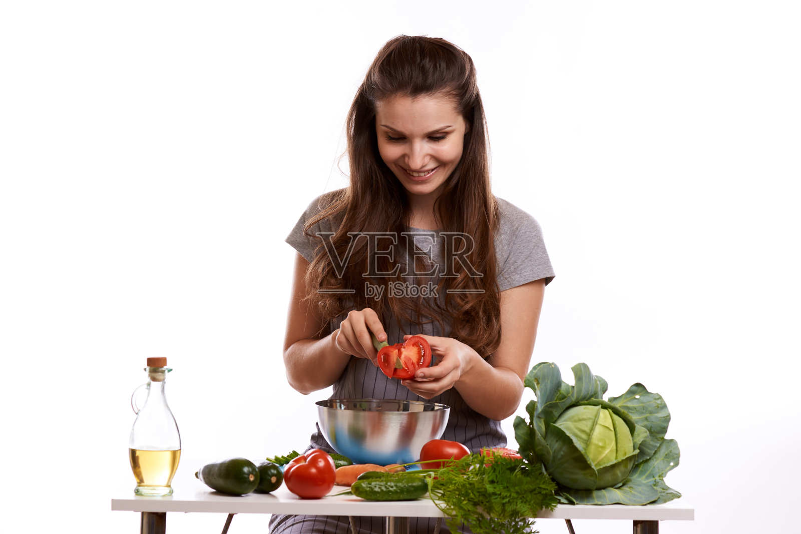 快乐的成年妇女用各种新鲜的蔬菜在厨房的桌子上看着相机照片摄影图片