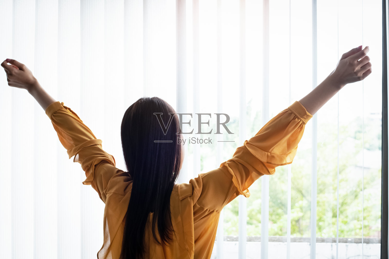 站在窗边的女士，把双手举在空中，放松心情照片摄影图片