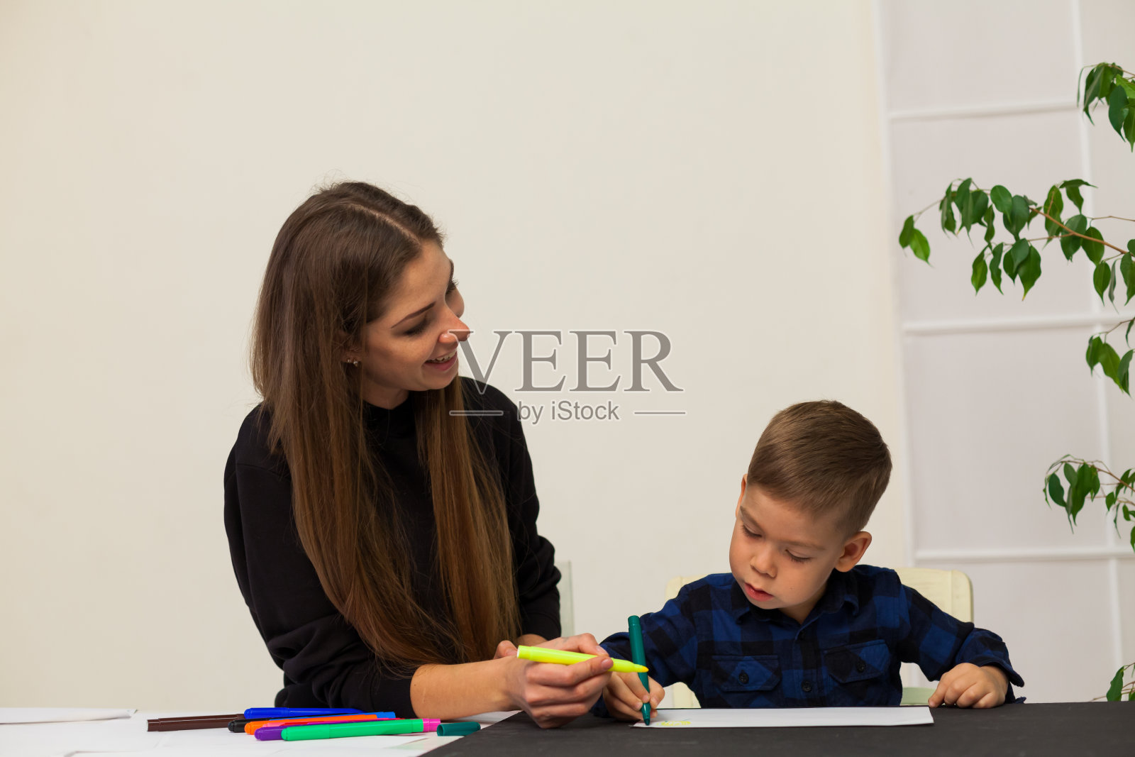 老师用小男孩的彩笔作画照片摄影图片
