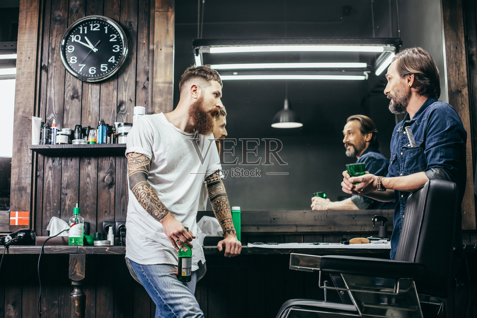 一个好奇的男人一边和他的同事喝啤酒一边看着他照片摄影图片