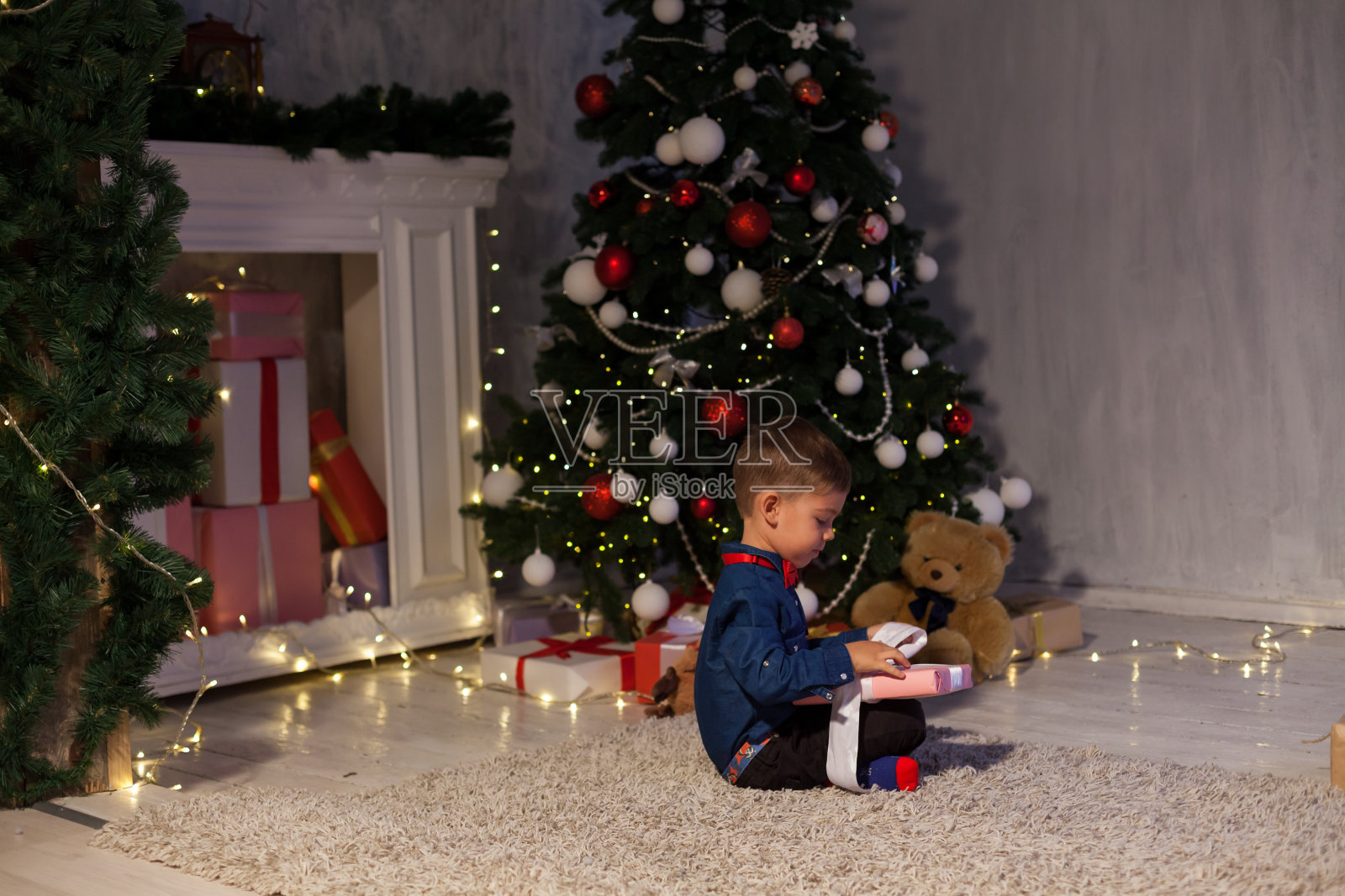 小男孩在圣诞新年的节日灯打开礼物照片摄影图片