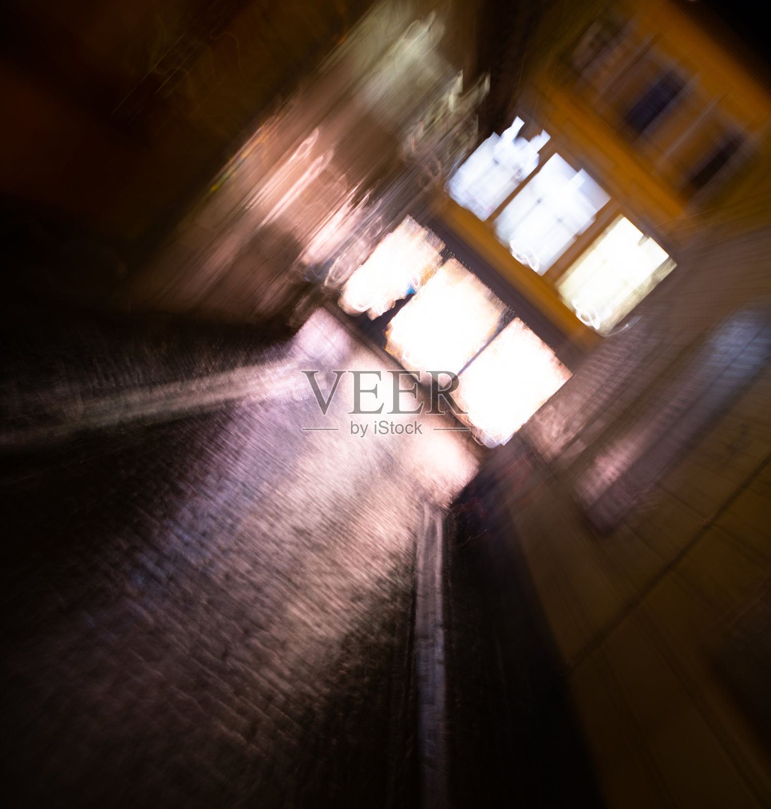 一个冬天的晚上，镜头模糊了老城“Gamla Stan”。街灯在雨水中反射着潮湿的鹅卵石照片摄影图片