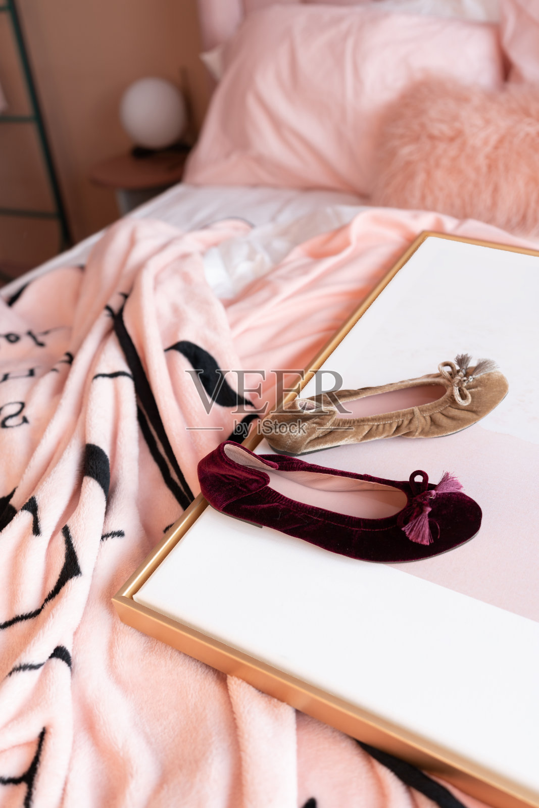 彩色的鞋子设置在金色框架与折皱的粉色毯子下面/舒适的室内概念/时尚照片与创意的背景照片摄影图片