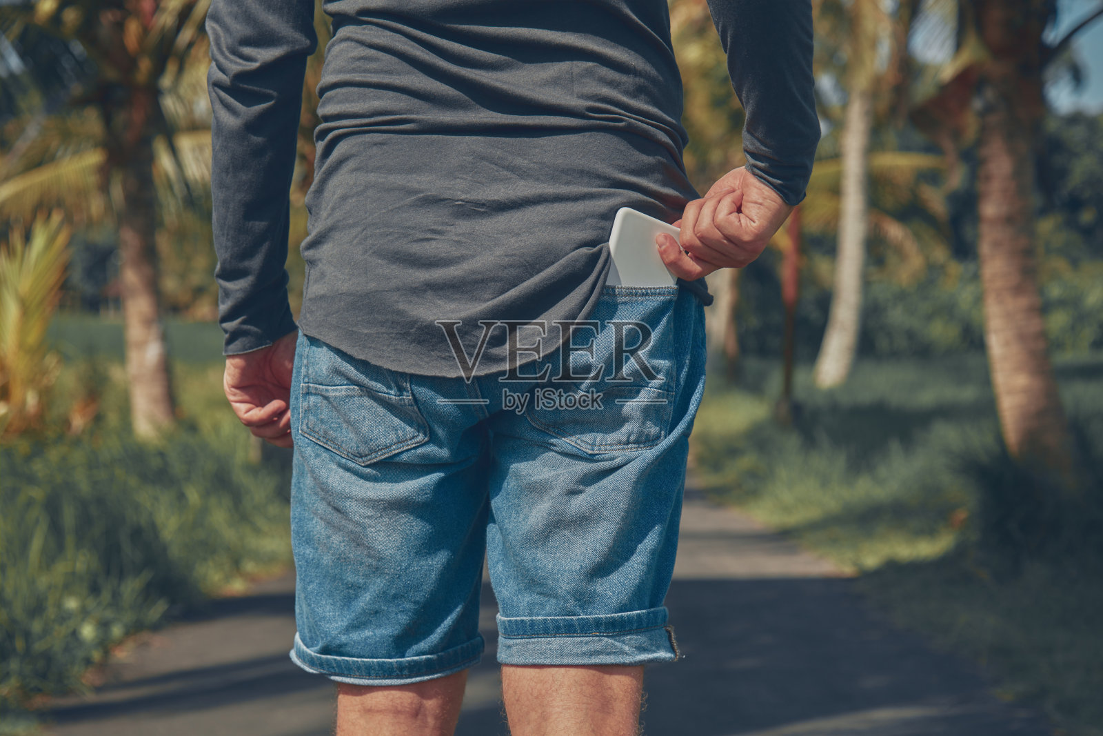男人从后面的口袋里拿出他的智能手机。照片摄影图片