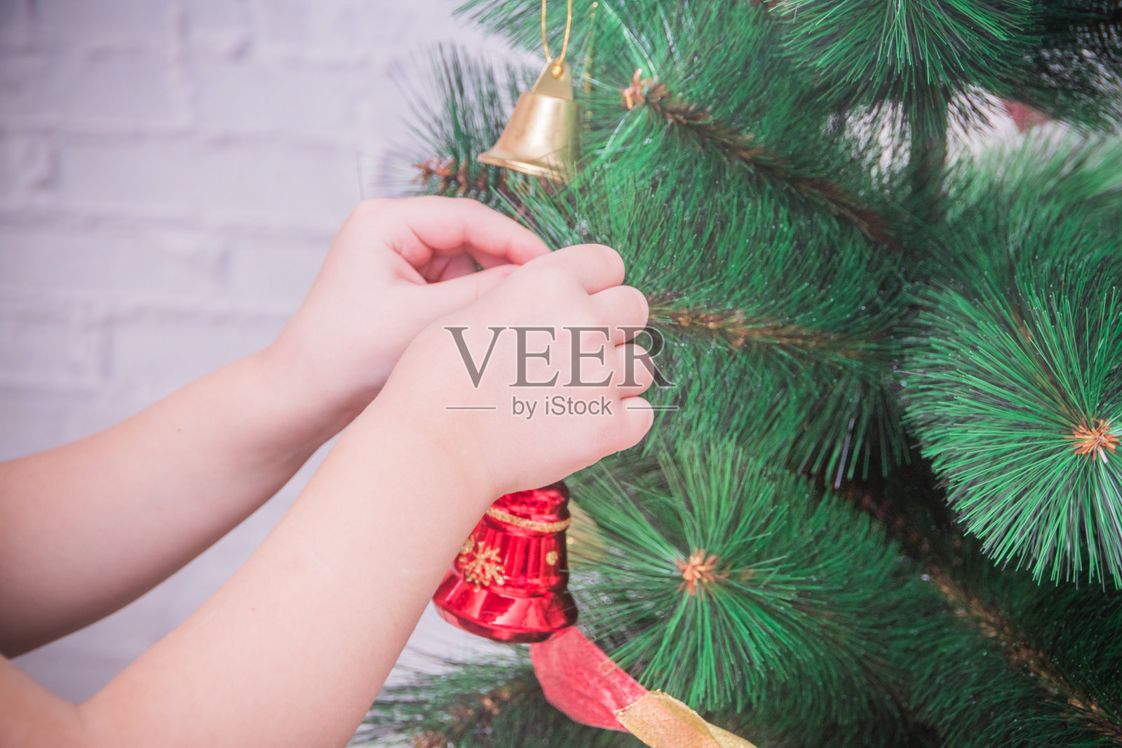 女孩、孩子在白色砖墙背景上装饰圣诞树照片摄影图片