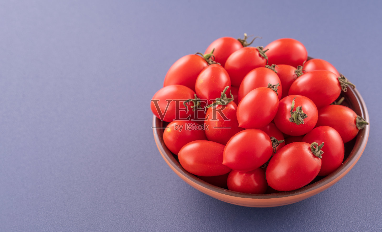 新鲜的红色樱桃番茄在一个木碗孤立的蓝色背景，近距离，复制空间照片摄影图片