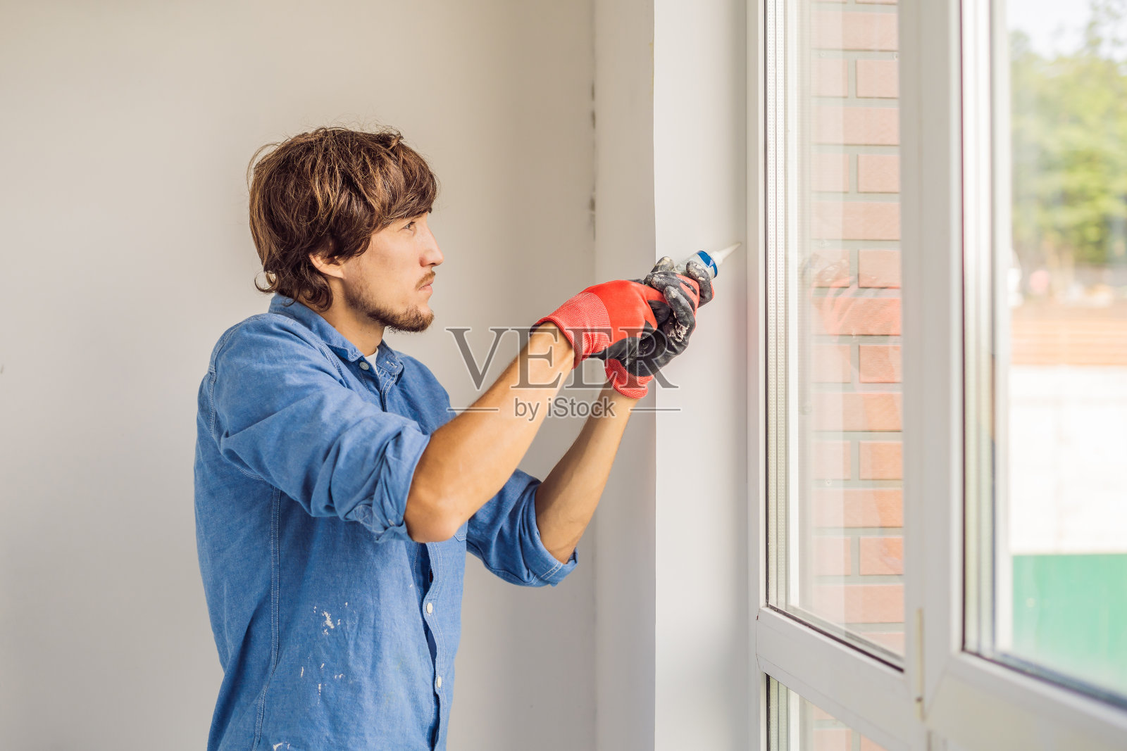 穿蓝色衬衫的人做窗户安装照片摄影图片