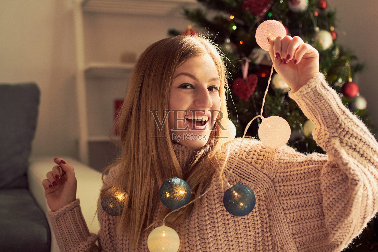 美丽的女人在圣诞树旁享受的肖像。照片摄影图片