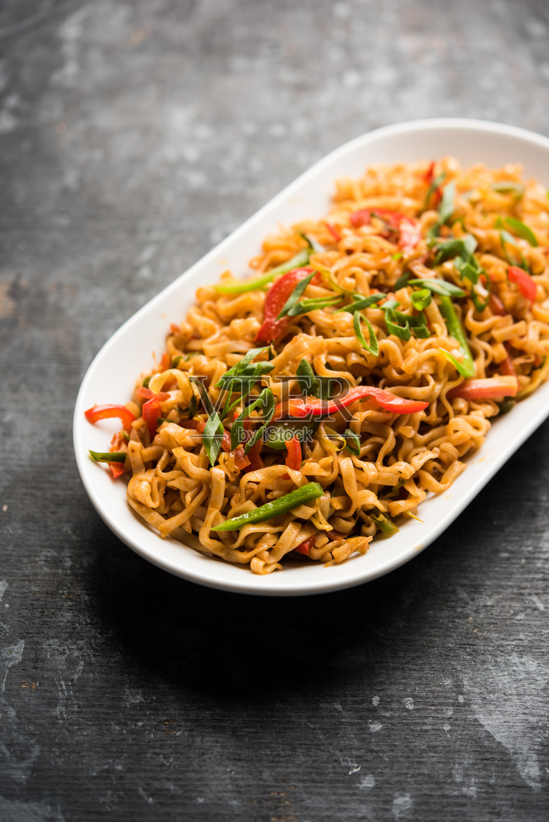 四川菜面是一种用酱料和蔬菜煸炒的客家扁面，味道辛辣可口。用筷子。有选择性的重点照片摄影图片