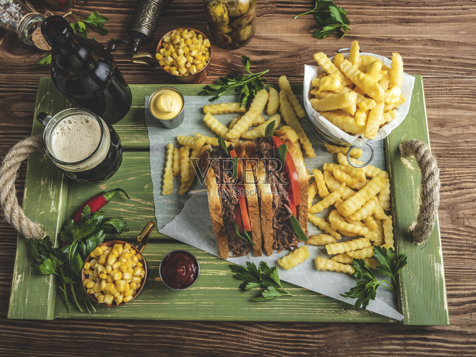 烤牛肉三明治，吐司，薯条，酱汁，黑啤酒，木托盘上的玉米照片摄影图片