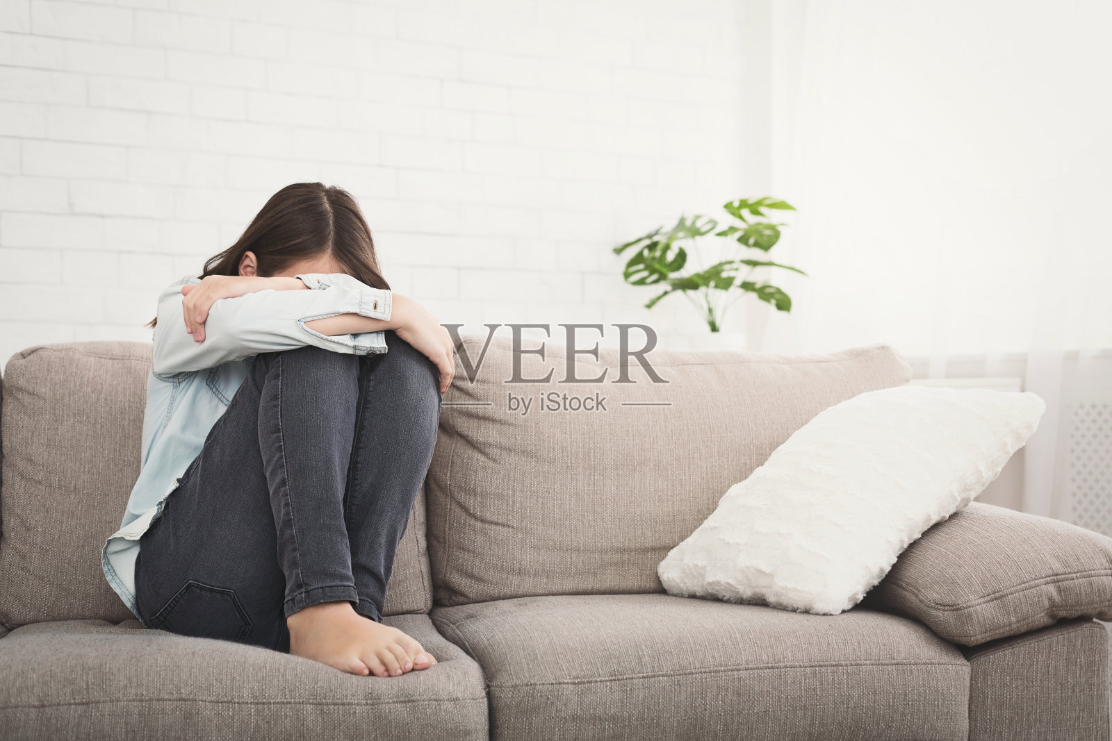 被冒犯的少女坐在沙发上感到孤独照片摄影图片
