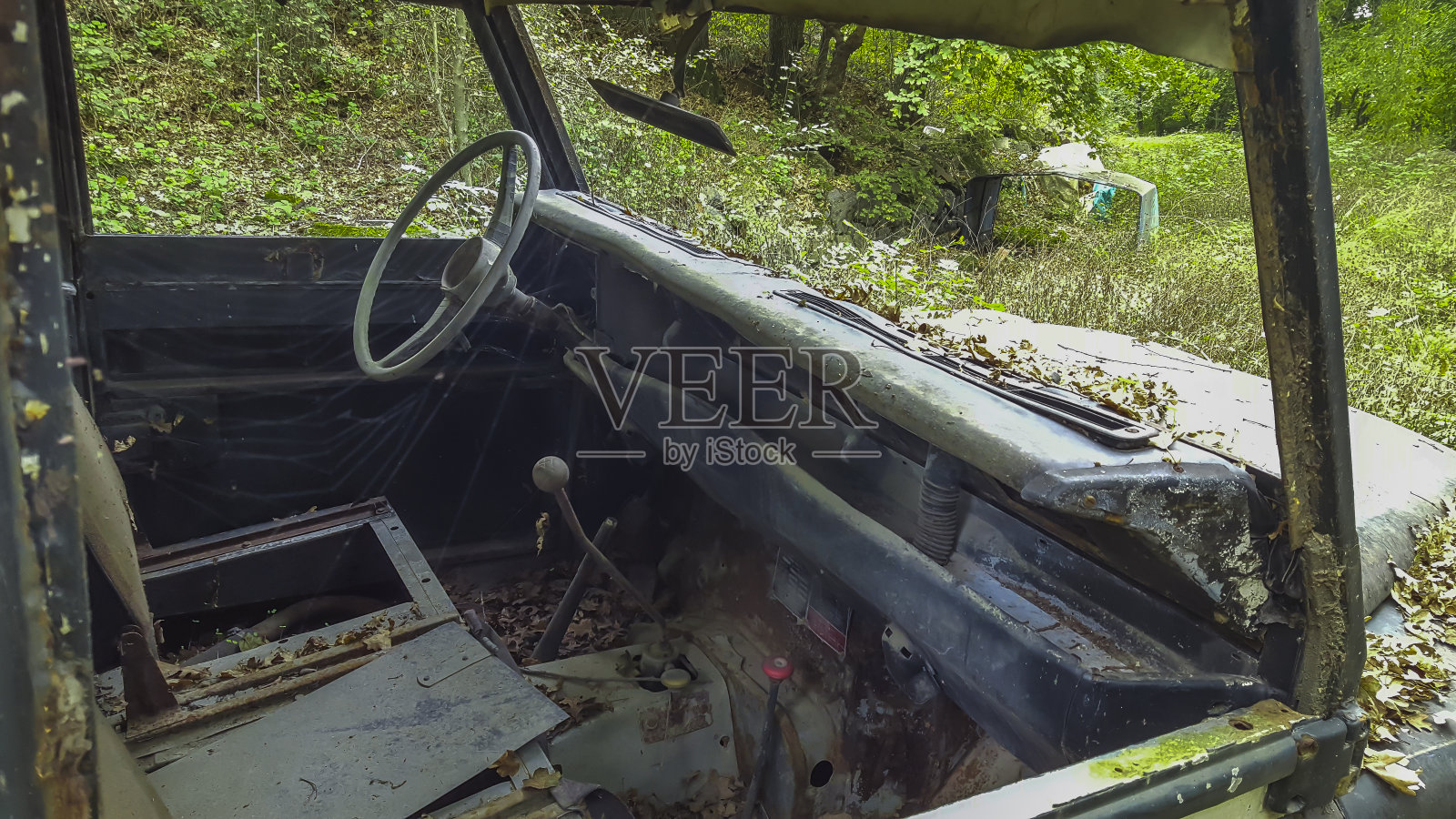一辆被遗弃在森林里的旧吉普车的特写。照片摄影图片