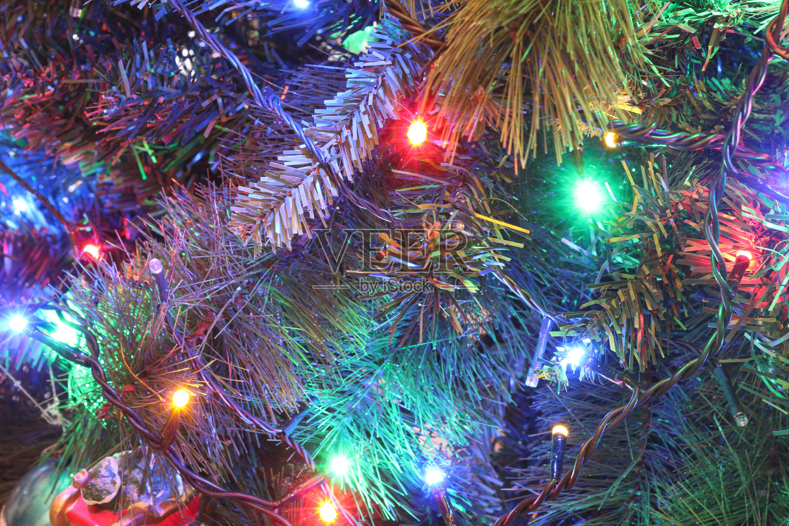 近距离观看一个绿色的树叶圣诞树与电灯装饰和悬挂的装饰品在一个明亮的彩色气氛照片摄影图片