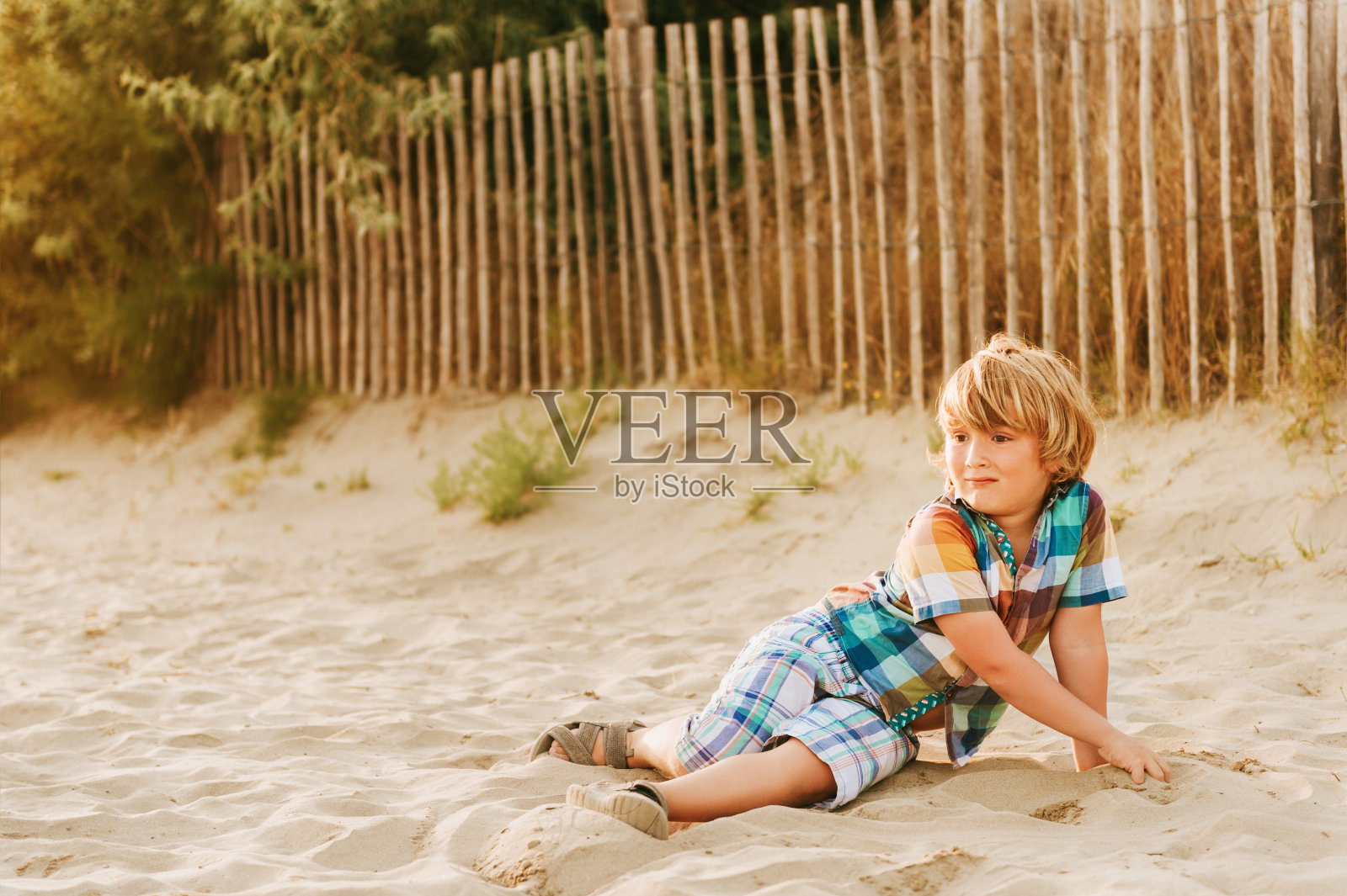 日落时分，有趣的小男孩在海边的沙滩上休息。小孩在法国南部享受暑假照片摄影图片
