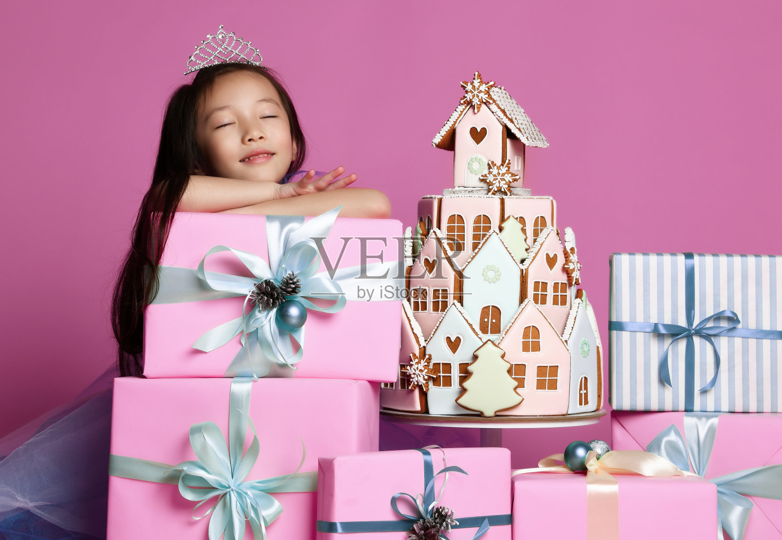 小亚洲女孩在皇冠和紫色的裙子与许多礼物礼盒和姜饼蛋糕庆祝生日照片摄影图片